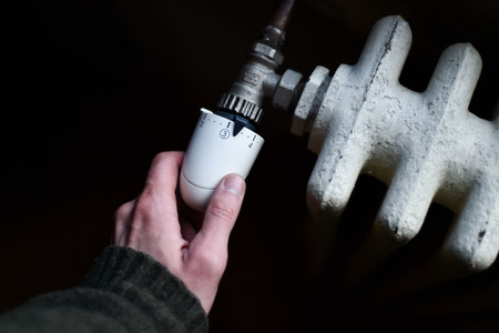 Detail with a hand checking the heat coming from a household radiatorの写真素材
