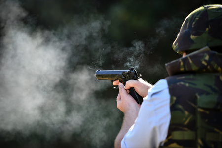 Outdoor target shooting with a 9mm pistol in a shooting rangeの写真素材