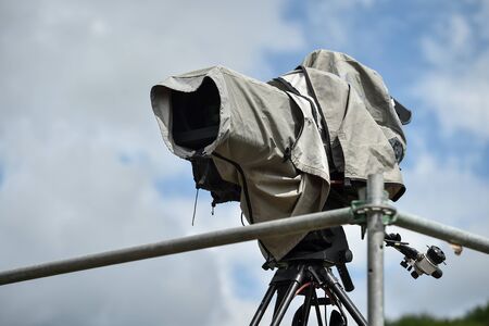 Television broadcast camera setup on a tripod and protected by a rain coverの写真素材