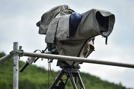 Television broadcast camera setup on a tripod and protected by a rain coverの写真素材
