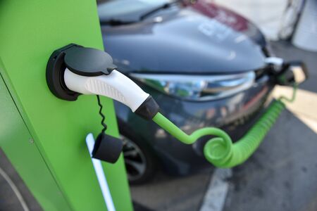 Electrical car plugged through a charging cable to a charging station.の写真素材