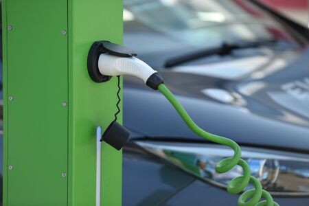 Electrical car plugged through a charging cable to a charging station.の写真素材