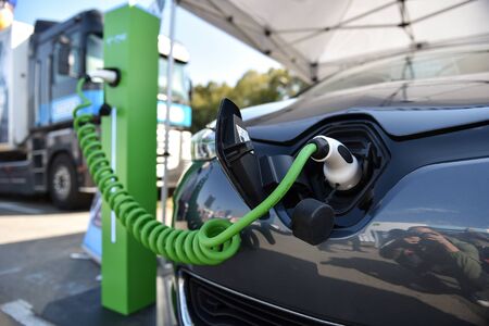 Electrical car plugged through a charging cable to a charging station.の写真素材