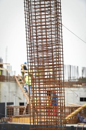 Detail with reinforcing iron bars on a construction site. Construction workers on the background.の写真素材