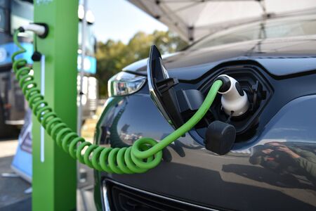 Electrical car plugged through a charging cable to a charging station.の写真素材