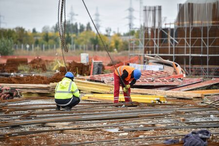 Detail with reinforcing iron bars on a construction site. Construction workers on the background.の写真素材