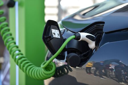 Electrical car plugged through a charging cable to a charging station.の写真素材