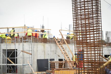 Detail with reinforcing iron bars on a construction site. Construction workers on the background.の写真素材