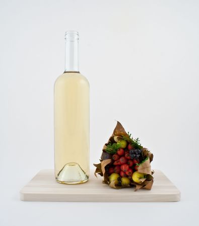 White wine bottle and bouquet of autumn dry fruit on rustic chopping board.の写真素材