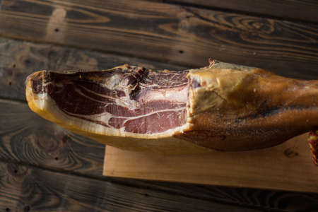 Whole serrano ham on a wooden table background.
