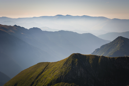 Fog in the mountains, three mountain ranges with a blue sky on the horizonの写真素材