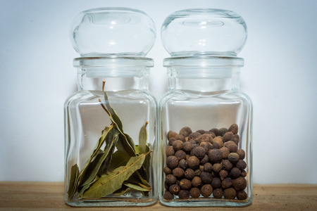 Bay leaves and allspice in a glass jar on the wooden shelfの写真素材