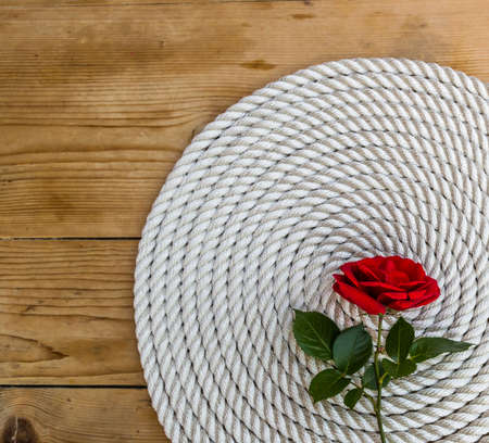 Beautiful red rose lily over rope and wooden tableの写真素材