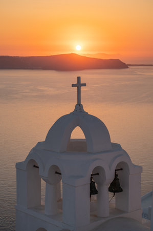 Santorini, white church against colorful sunset in Greeceの写真素材