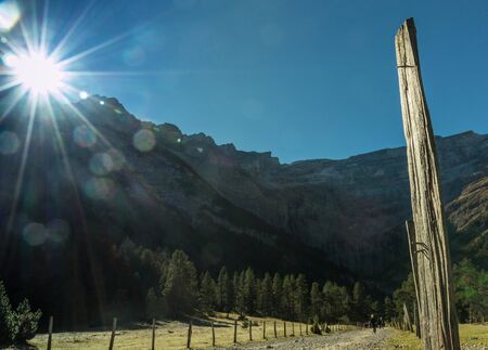 Fence for cattle in a mountain landscape with sun and sky in the backgroundの写真素材