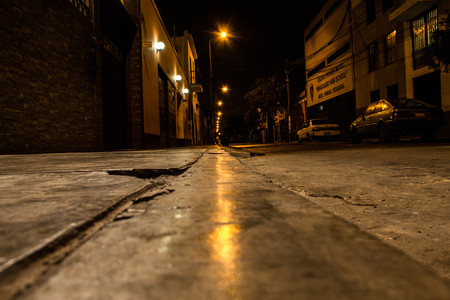 Picture of the sidewalk of a street at night with the reflection of the light from the street lampsのeditorial素材
