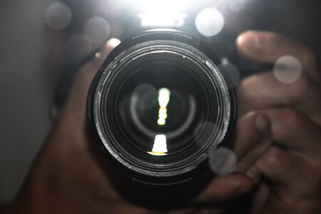 Lens of a reflex camera with hands holding it in placeの写真素材