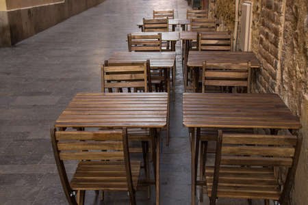 Rustic wooden tables and chairs from a restaurant terraceの写真素材