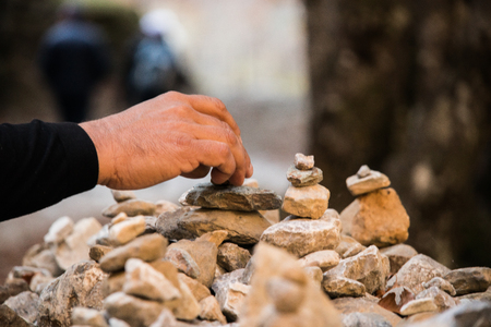 Stones piled up on the mountain with one hand putting them in place. Symbol of peaceの写真素材