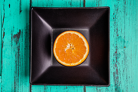 Cut orange on a plate and blue rustic table