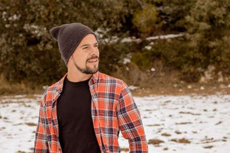 Pensive man with beard plaid t-shirt, hat and casual clothing. A young and carefree lifestyle. Snow bottomの写真素材