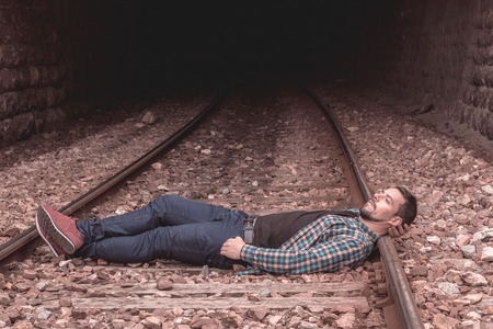 Boy with a thoughtful face and serious attitude. Picture on the train tracks, man dressed casual. Portraitの写真素材