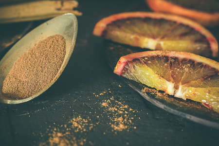 Blood oranges and cinnamon. Spoon with cinnamon and napkins. Moody food and dark food.の写真素材