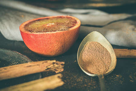 Blood oranges and cinnamon. Spoon with cinnamon and napkins. Moody food and dark food.の写真素材