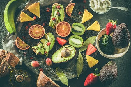 Assorted fruits on a plate. Avocados, blood oranges, kiwis, pineapple and strawberries. Healthy food and trendy fruits.の写真素材