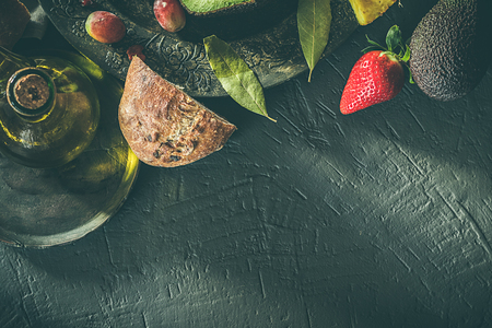 Healthy food: Avocado, pineapple, strawberries and grapes with bread and oil. Moody food concept. Dark foodの写真素材