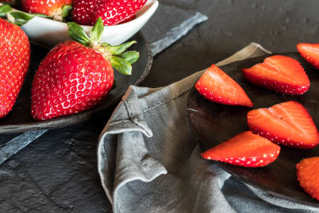 Strawberries cut and whole on a plateの写真素材