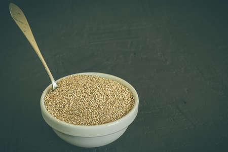 Quinoa seeds in a bowl and spoon. Healthy, protein-rich carbohydrates. Rustic and dark backgroundの写真素材
