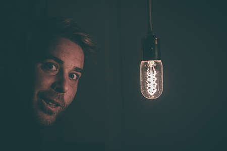 Boy smiling with a light bulb on his face. Concept of ideaの写真素材