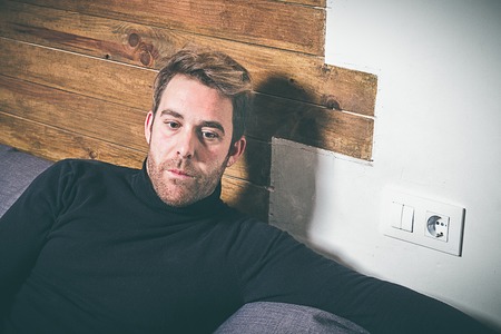 Handsome blond boy, thoughtful at home. Expression with a blank stare. Vintage style photo. Young Lifestyleの写真素材