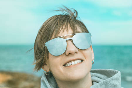 Portrait of a normal girl with smiling sunglasses on the beach. Cheerful woman on the beachの写真素材