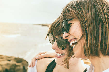 Two young girls smiling by the sea. Sensation of happiness