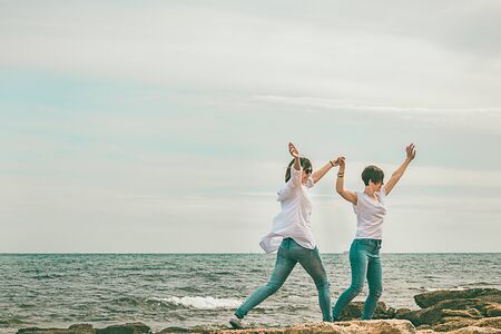 Normal girls on the beach with their arms raised. Dressed in white. Sensation of happiness