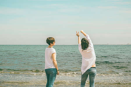 Women practicing yoga on the beach. Hands up. Dressed in whiteの写真素材