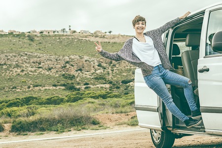 Girl leaning out the door of a van. Concept of travel and happiness