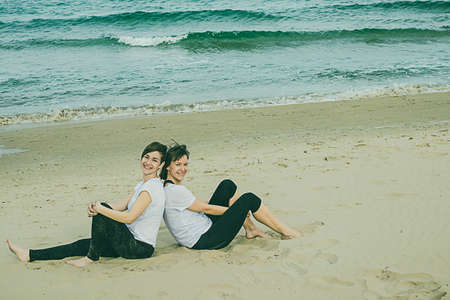 Normal women on the beach smiling and sitting on the sand. Young girlsの写真素材