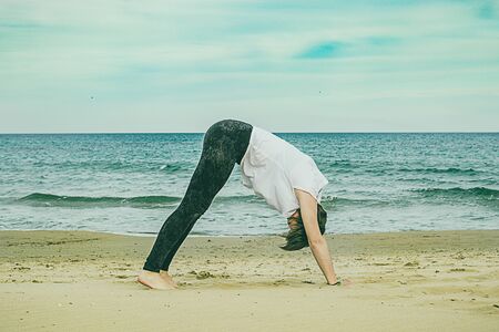 Girl doing yoga poses on the beach. Practicing a healthy lifestyle