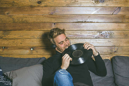 Guy with music helmets and vinyl in his hands. Concept of music, social networking photographyの写真素材