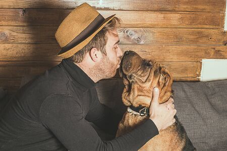Young man playing with his dog at home.Dog of shar-pei breed brown colorの写真素材