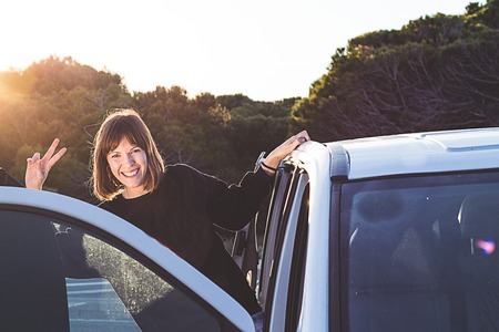 Young girl smiling, holding on to the door of a car... Concept of travel and freedom