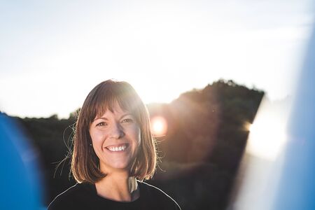 Woman smiling with the sun behind her. Brunette girl with a happy attitudeの写真素材