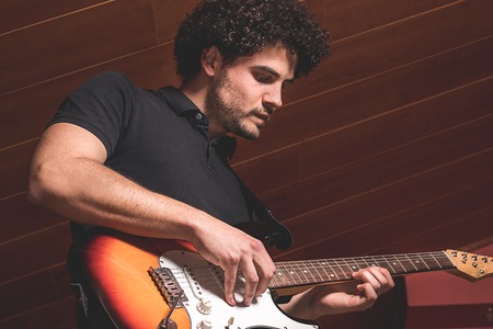 Close-up of a guy playing the electric guitar. Concept of musicの写真素材