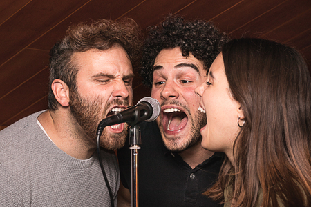 Three singers singing with a microphone with euphoric expression. Concept of musicの写真素材