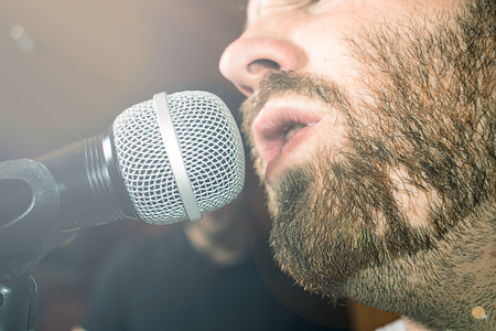 Close-up of a guy with a beard singing on a microphone. Concept of music