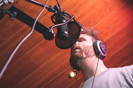 Singer singing in a music studio with microphone and headphonesの写真素材