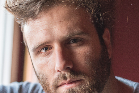 Portrait of a young guy with modern hair and serious face and beardの写真素材